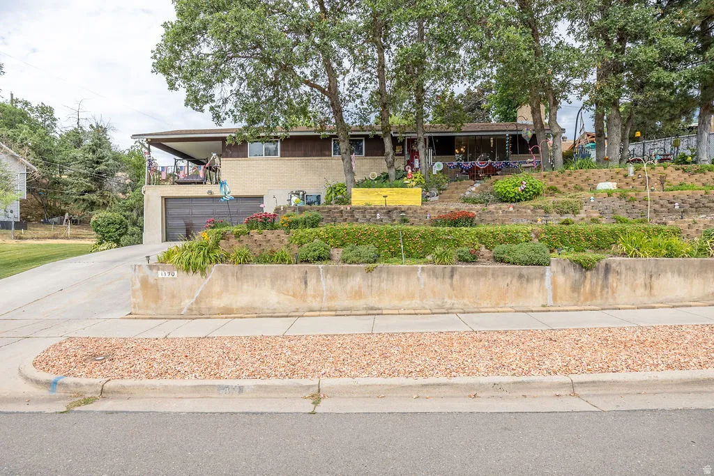 Multi-level landscaping featuring established trees and terraced planting beds