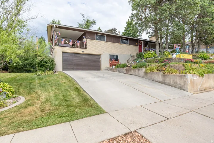 Split-level residence featuring a two-car garage, concrete driveway, and a front balcony