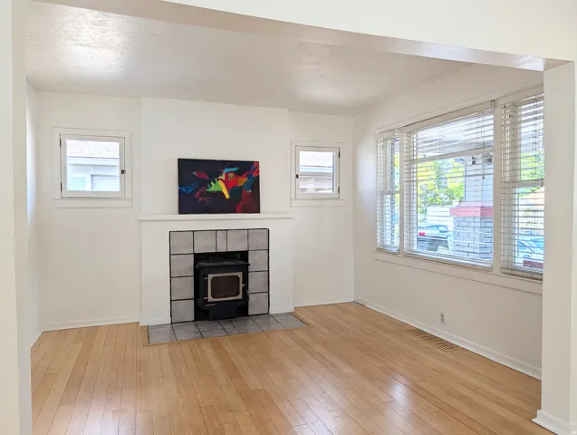 Spacious interior featuring light wood-finish flooring, a fireplace with a tiled surround, and multiple windows