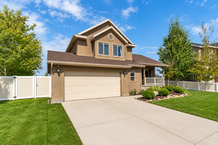 Stucco exterior residence with a two-car garage, concrete driveway, and covered front porch