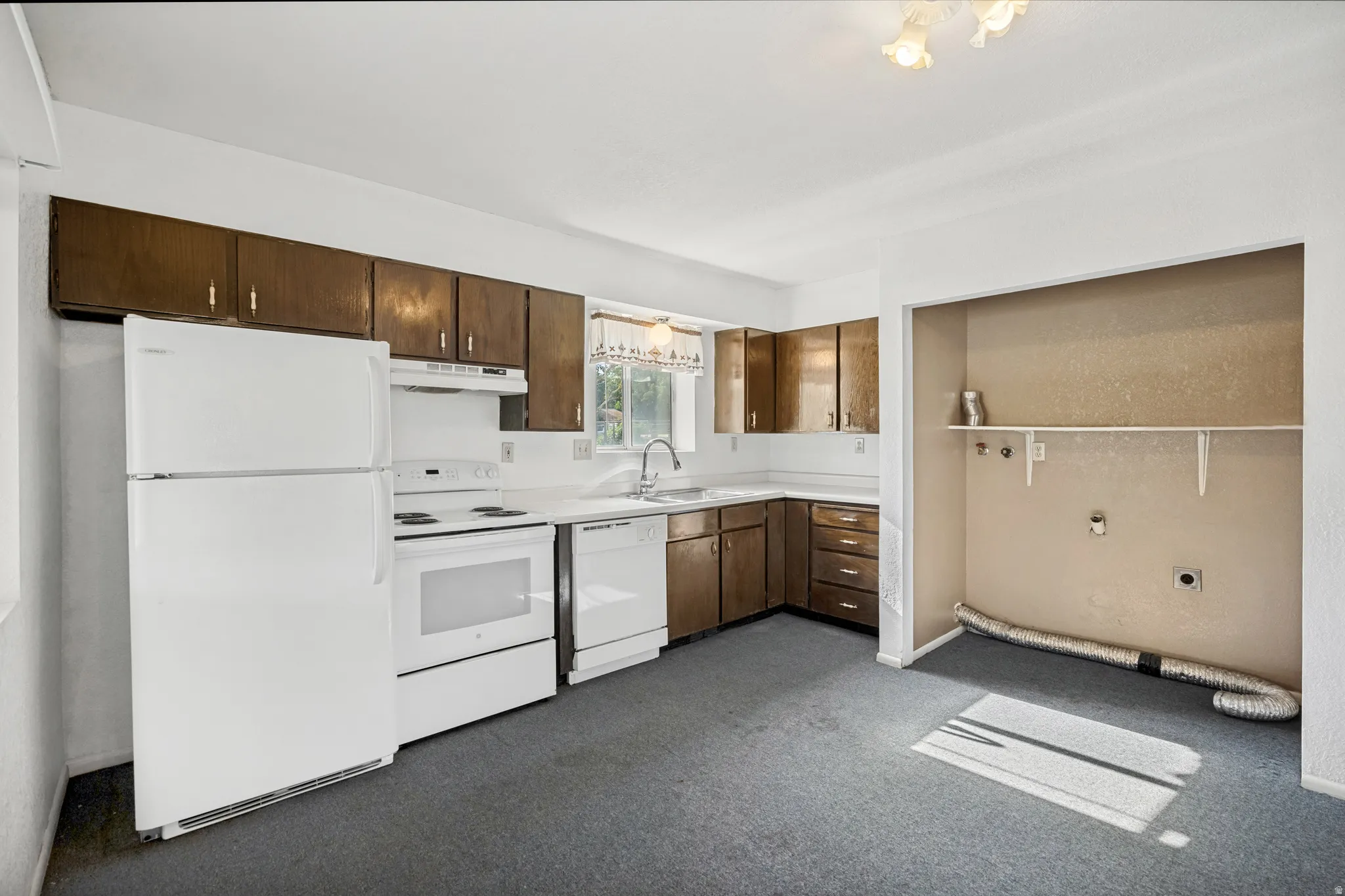 Kitchen featuring white appliances, dark wood-finish cabinetry, white countertops, and a double basin sink