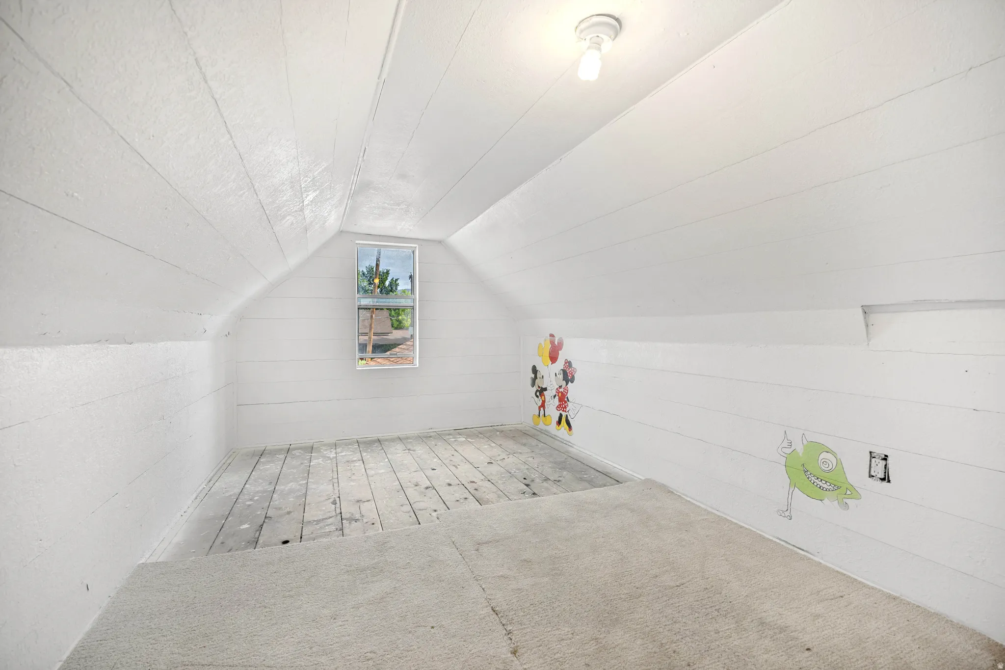 Attic space featuring white painted horizontal paneling, gabled ceiling, and a single-pane window