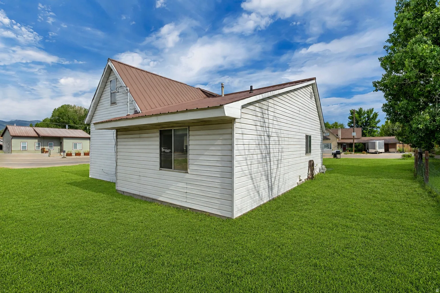 White siding exterior featuring a brown metal roof and a prominent gable