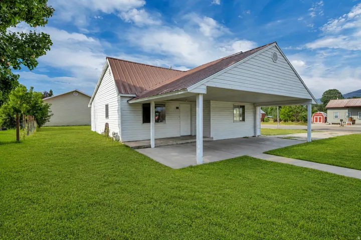 White siding exterior with a brown metal roof, featuring an attached carport and a concrete driveway