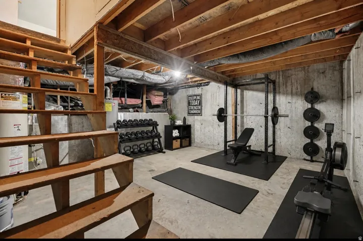 Unfinished basement space featuring exposed wood beam ceilings, concrete walls, and concrete flooring