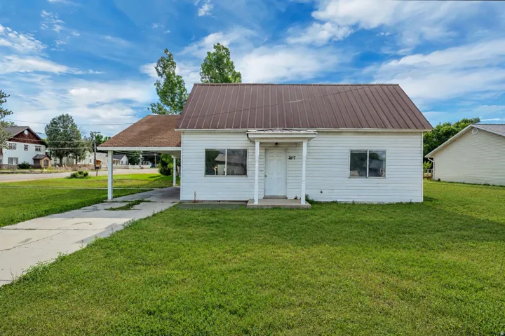 Single-story home featuring a metal roof, white siding, and a covered carport