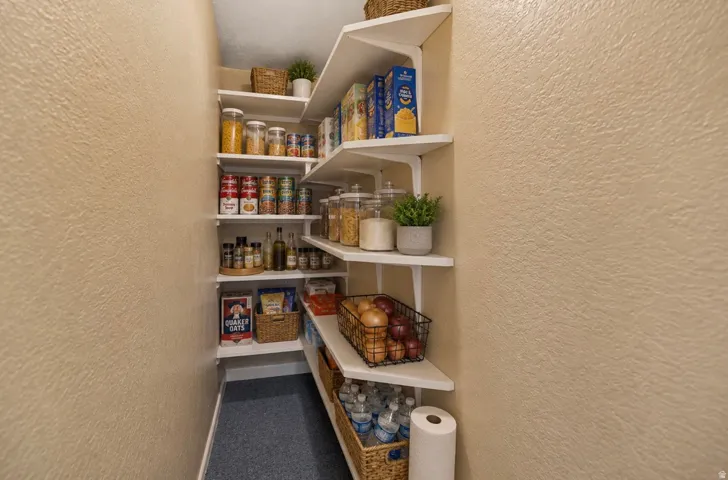 Built-in pantry shelving with white finishes and textured wall surfaces