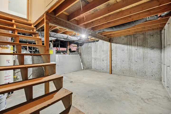 Unfinished basement space featuring exposed wood joists and concrete flooring