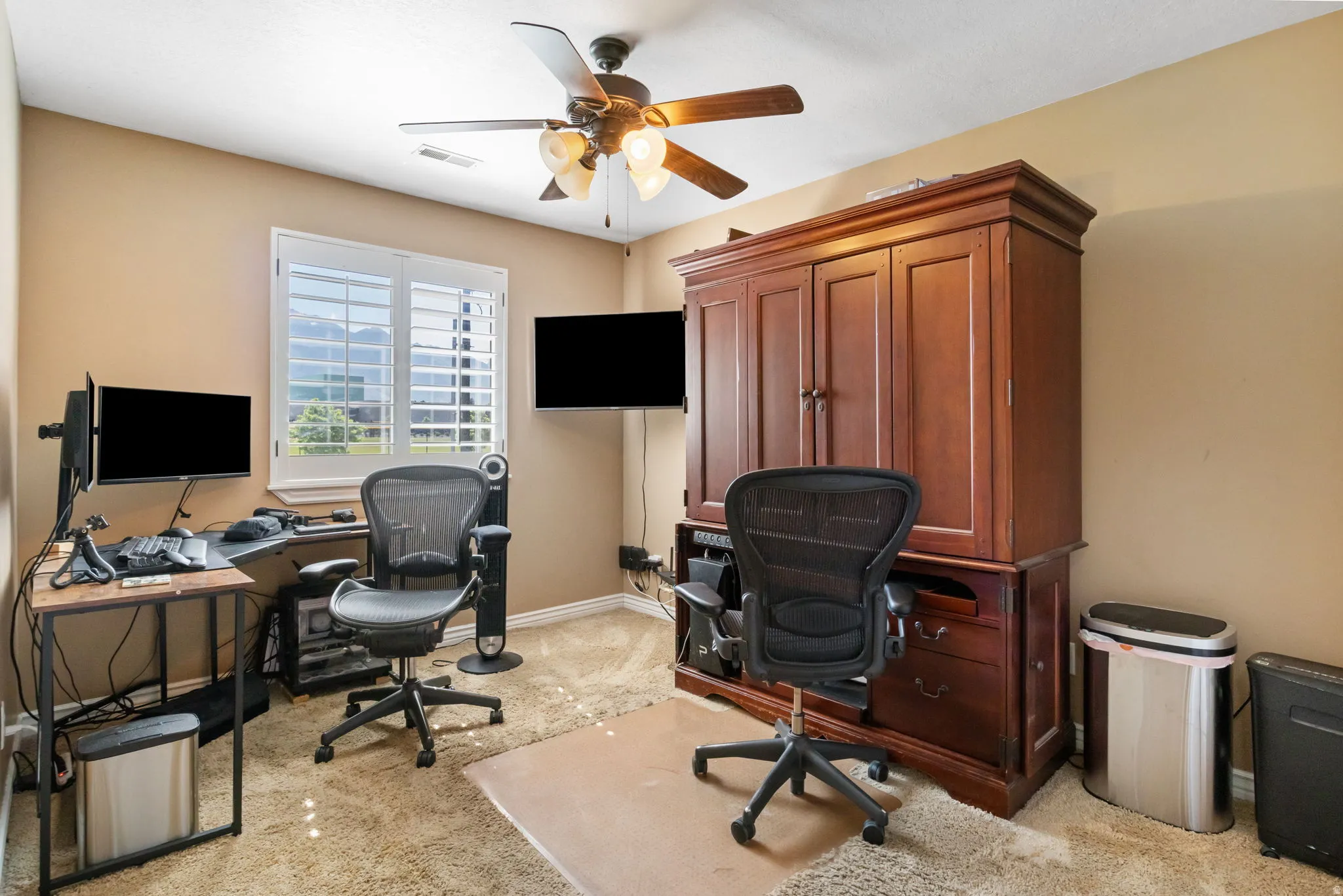 Versatile room featuring a window with plantation shutters, ceiling fan, and carpeted flooring