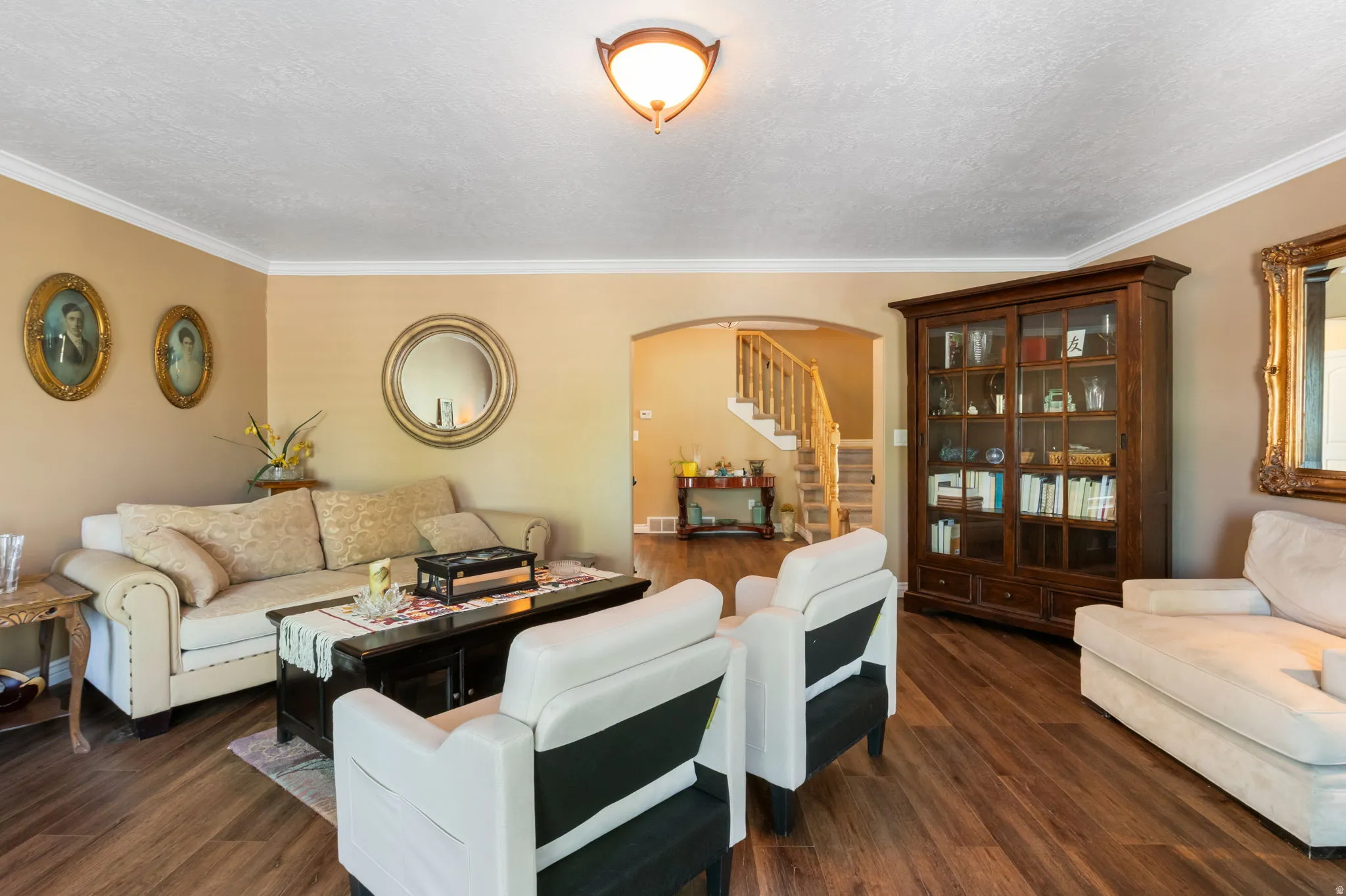 Warm living space featuring wood-finish flooring, neutral wall tones, and crown molding
