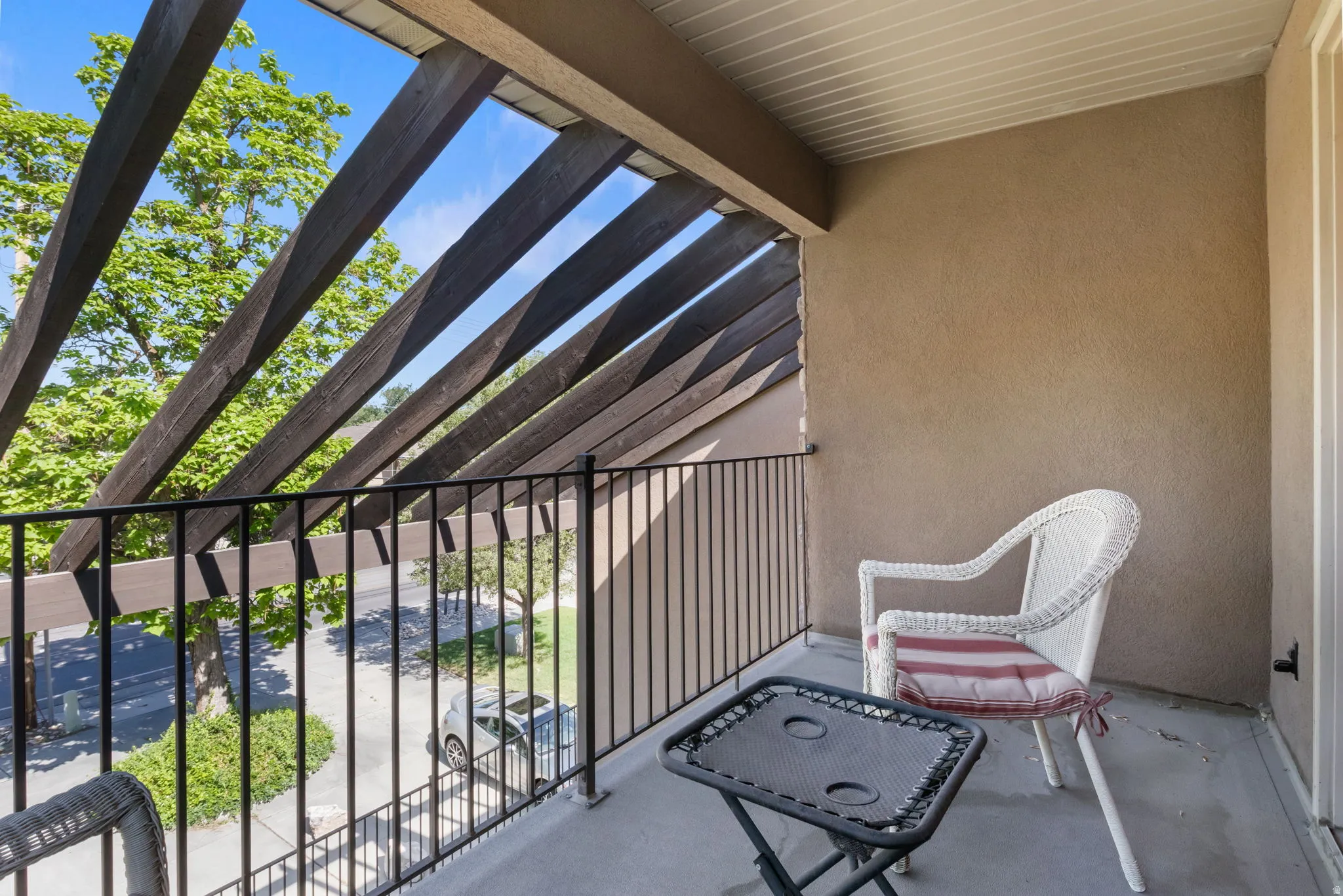 Balcony featuring stucco walls, a flat ceiling, and a black metal railing