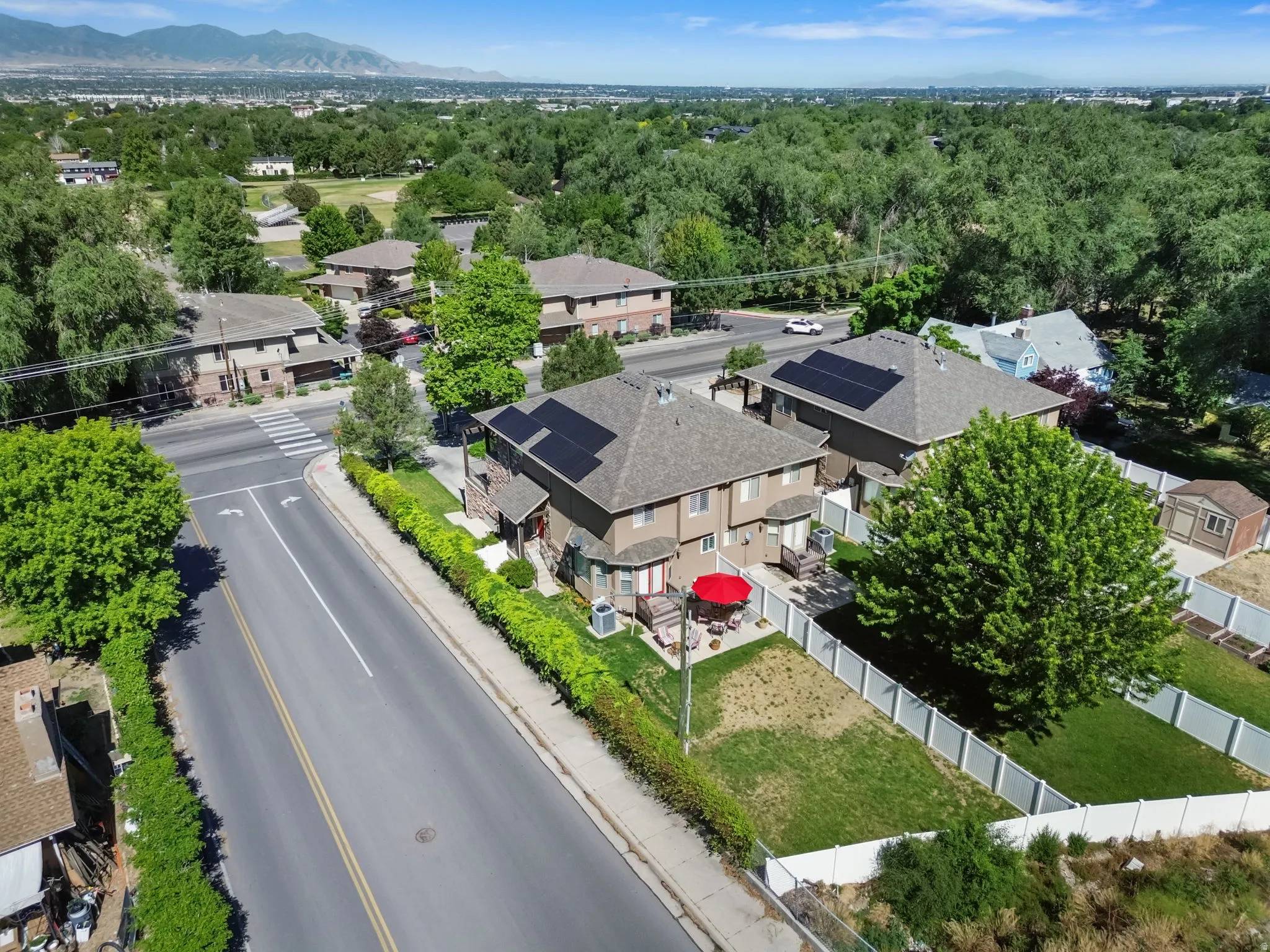 Multi-level townhome featuring a neutral-toned exterior, gabled roofline with solar panels, and a private rear patio