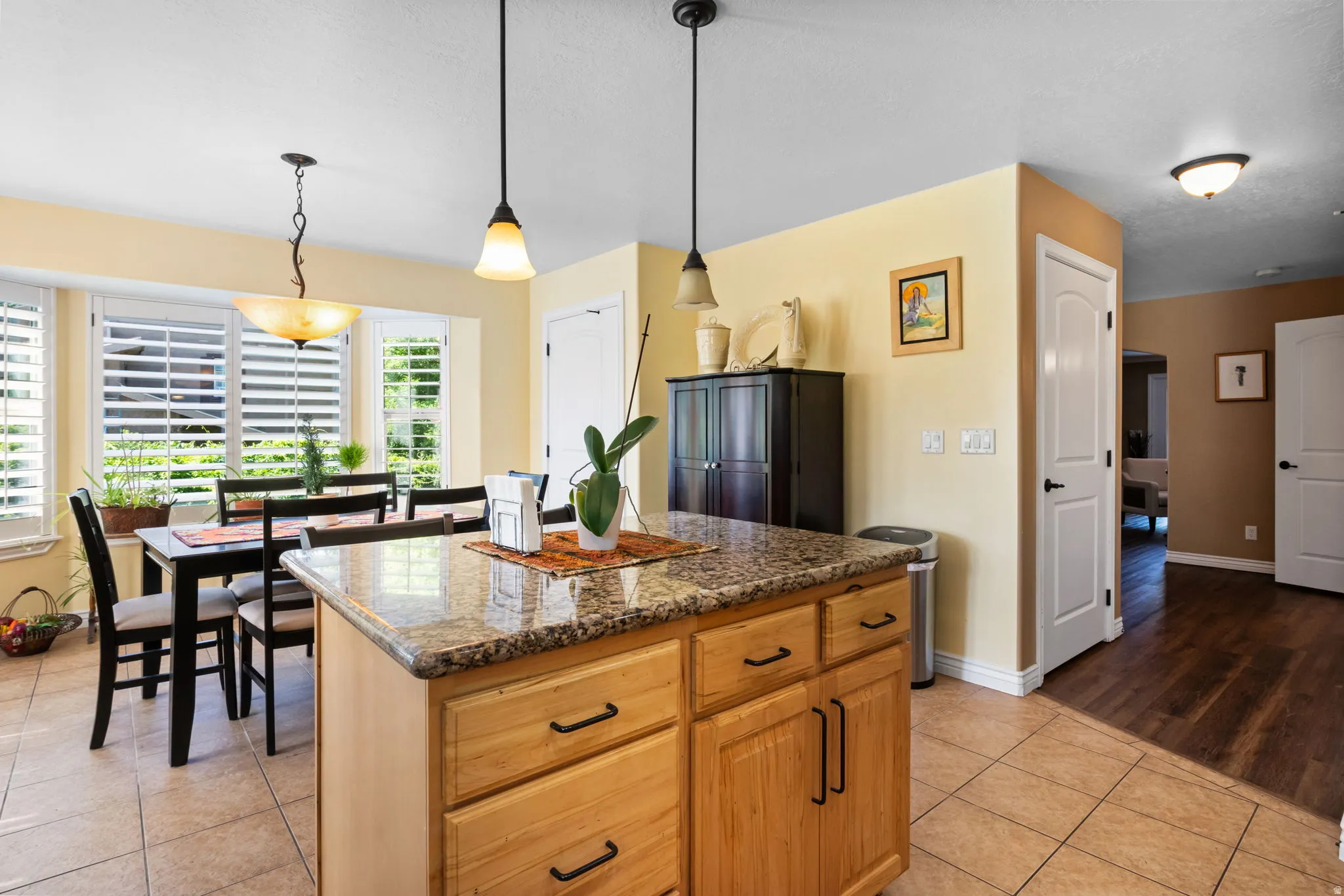 Kitchen featuring a central island with a stone countertop and wood cabinetry, pendant lighting, and tile flooring