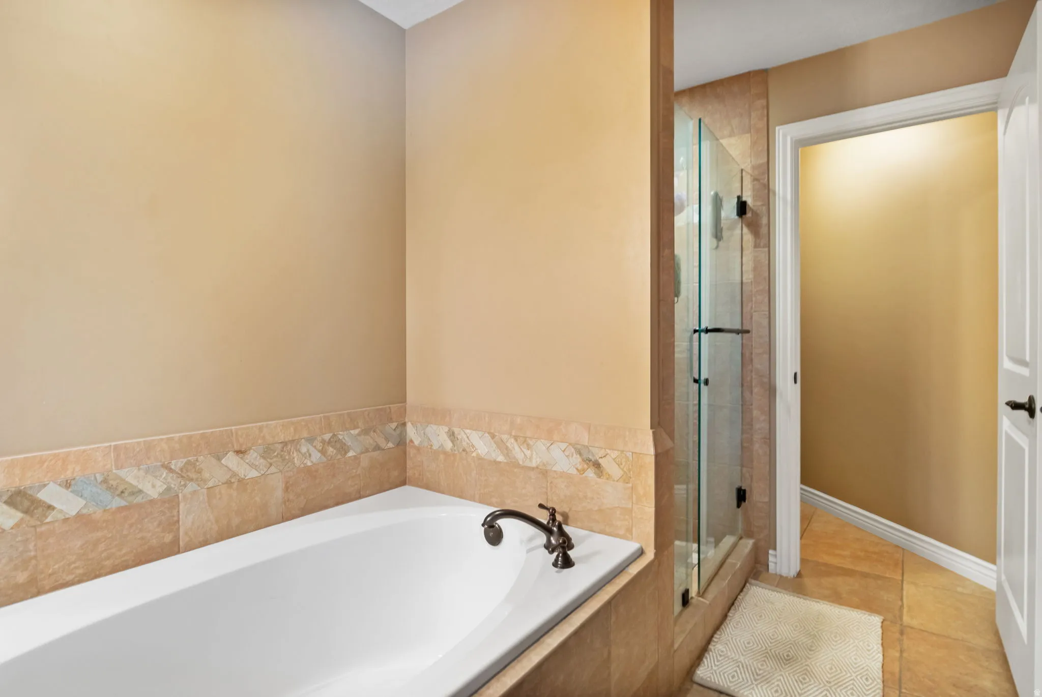 Soaking tub with bronze faucet, surrounded by natural stone-look tile