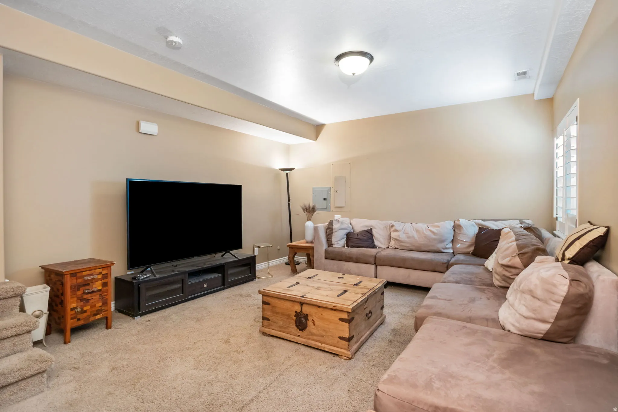 Carpeted living area featuring a built-in window shutter, recessed ceiling light, and neutral wall tones