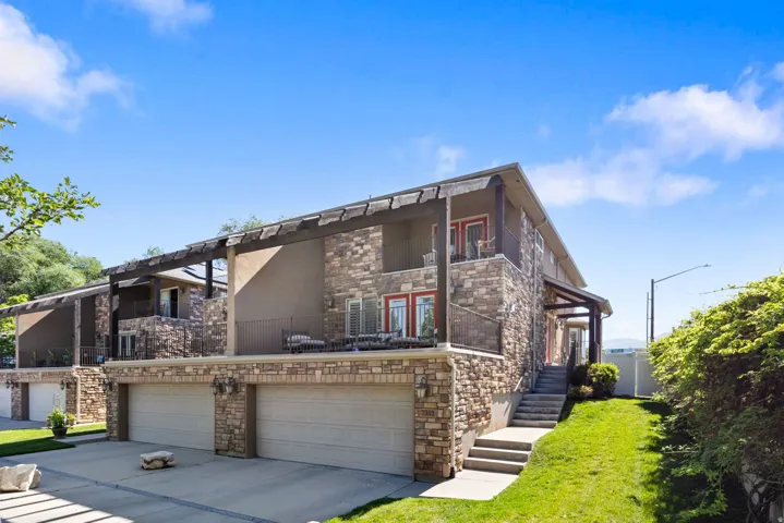 Multi-level exterior featuring a stone and stucco facade, private balconies with pergolas, and two-car garages