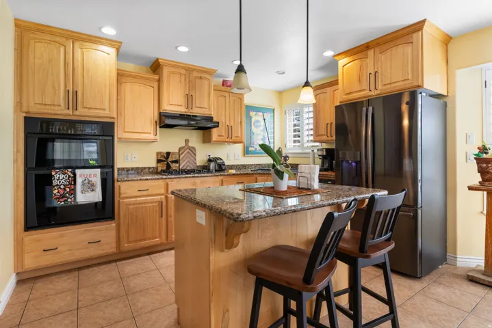 Kitchen featuring wood-finish cabinetry, granite countertops, and a built-in double oven