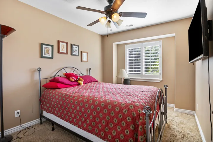 Carpeted room featuring a ceiling fan with integrated lighting, a window with plantation shutters, and baseboard molding