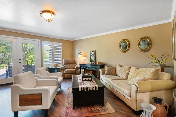 Living area featuring warm-toned walls, wood-finish flooring, and crown molding