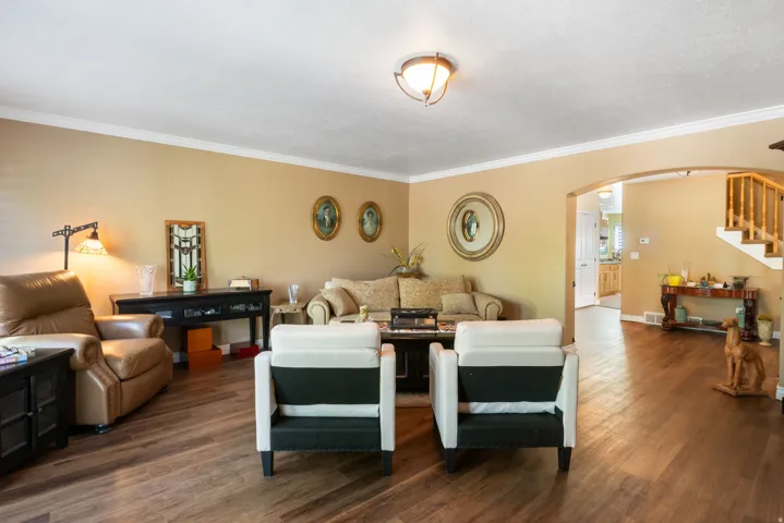 Spacious living area featuring wood-finish flooring, neutral wall tones, and crown molding