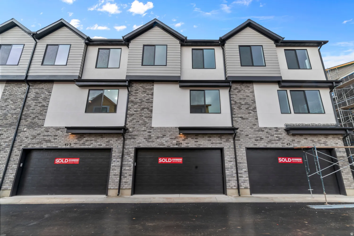 Contemporary multi-story townhome exterior featuring a striking combination of light brick and horizontal siding