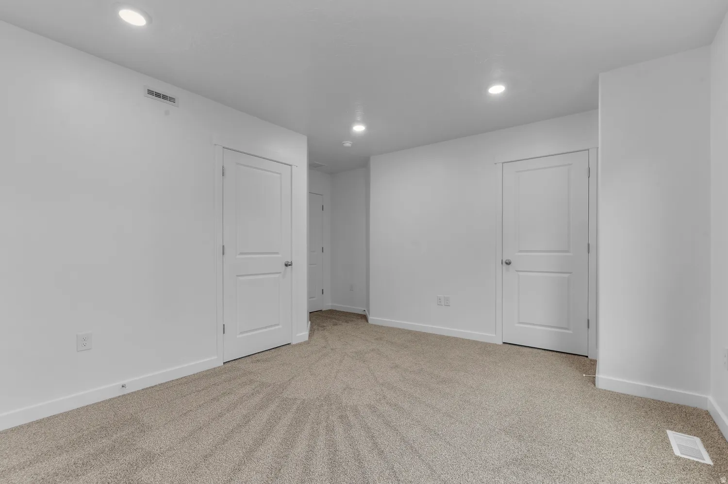 Carpeted room featuring white walls, recessed lighting, and multiple white two-panel interior doors