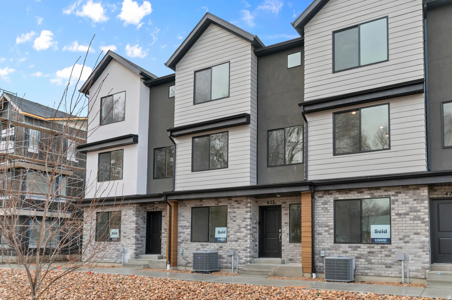 Contemporary townhome exterior featuring light gray siding, dark gray stucco, and gray brick veneer