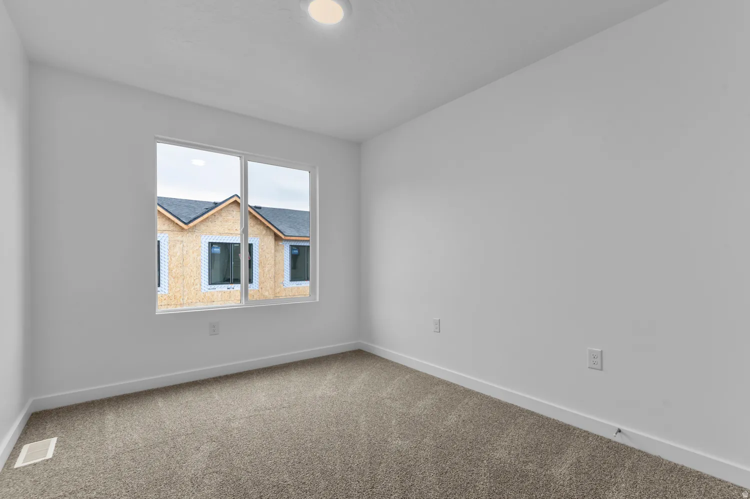 Neutral-toned carpeted room featuring white walls and baseboards