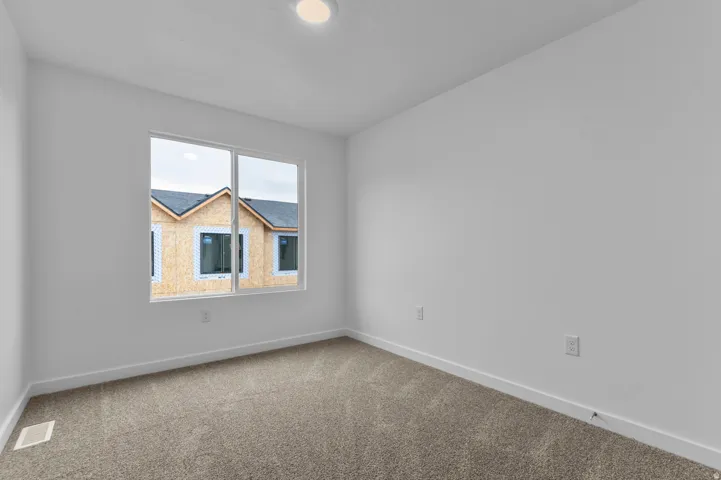 Neutral-toned carpeted room featuring white walls and baseboards