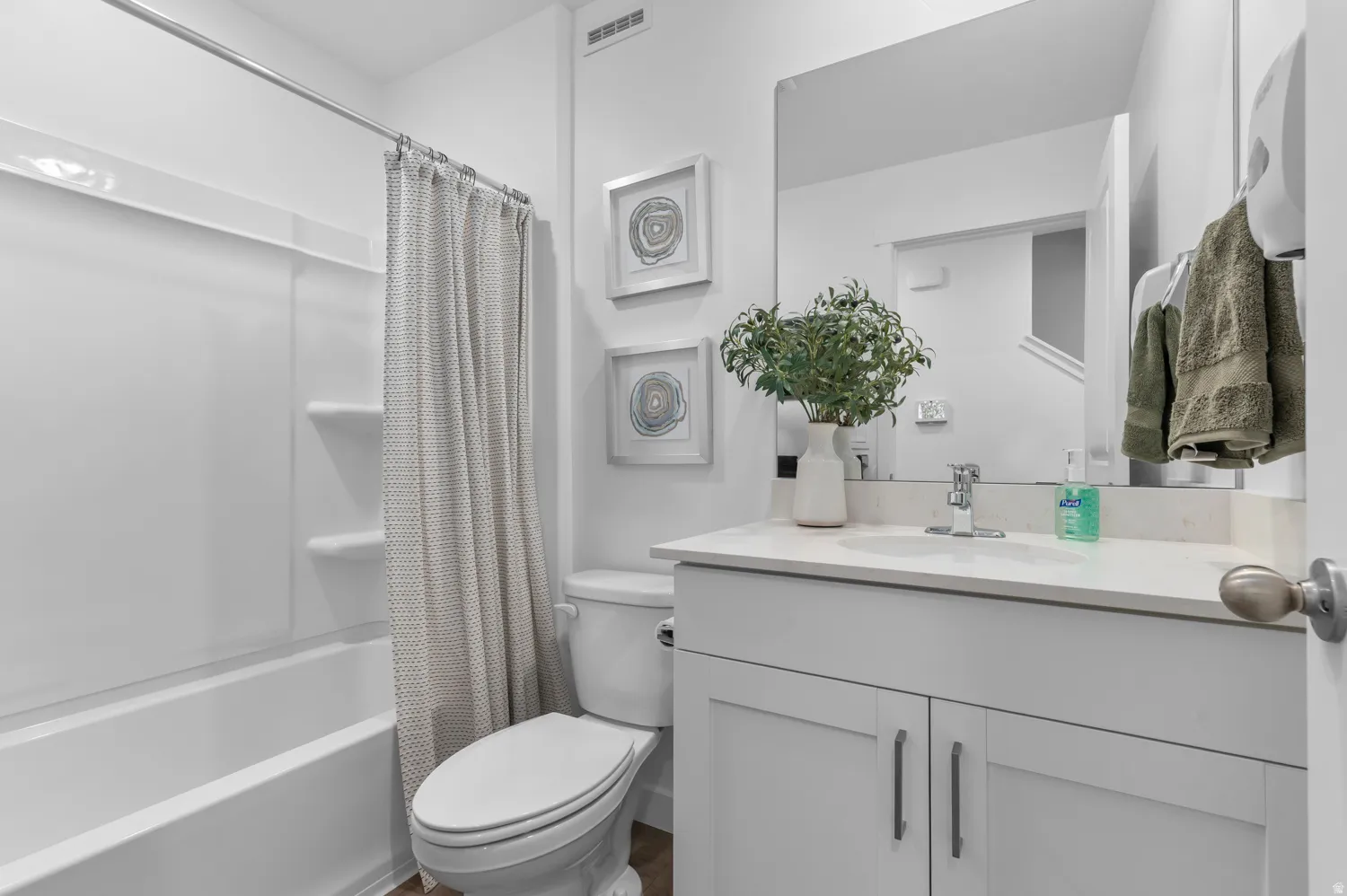 Bathroom featuring a single vanity with under-sink storage, a solid surface countertop, and a rectangular mirror