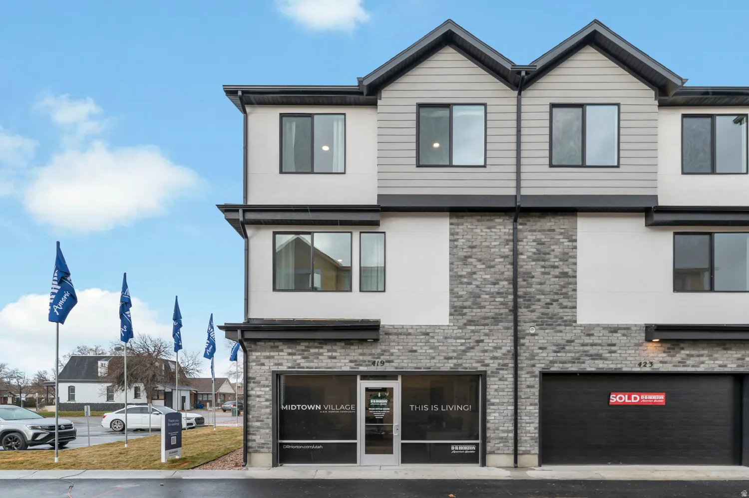 Contemporary multi-story exterior featuring a varied facade of light gray siding, white stucco, and textured gray brick