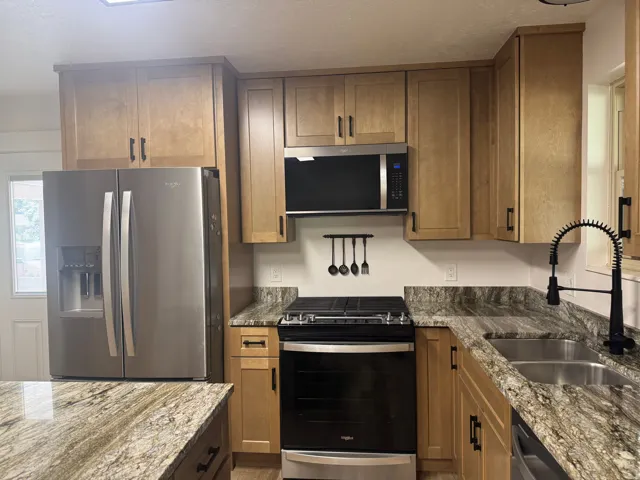 Kitchen featuring light wood-finish cabinetry, stainless steel appliances, and patterned countertops