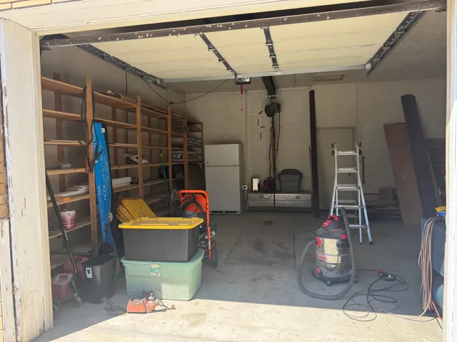 Garage with built-in wooden shelving, concrete flooring, and an overhead garage door