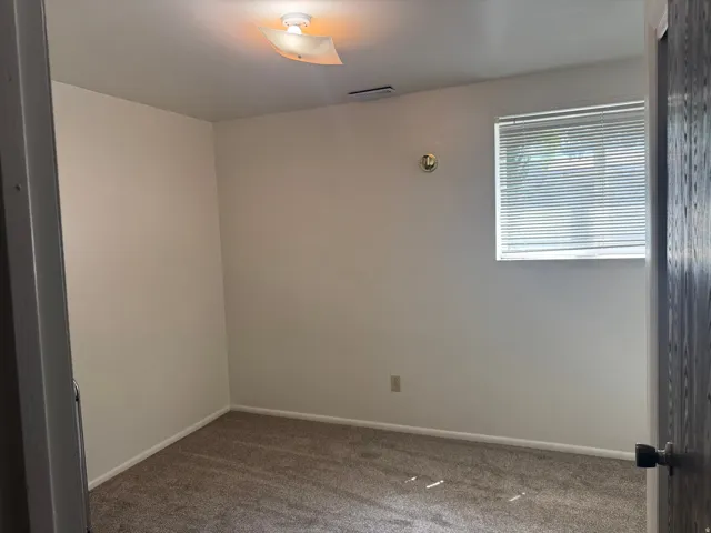 Neutral tone walls with white trim and a single window featuring horizontal blinds