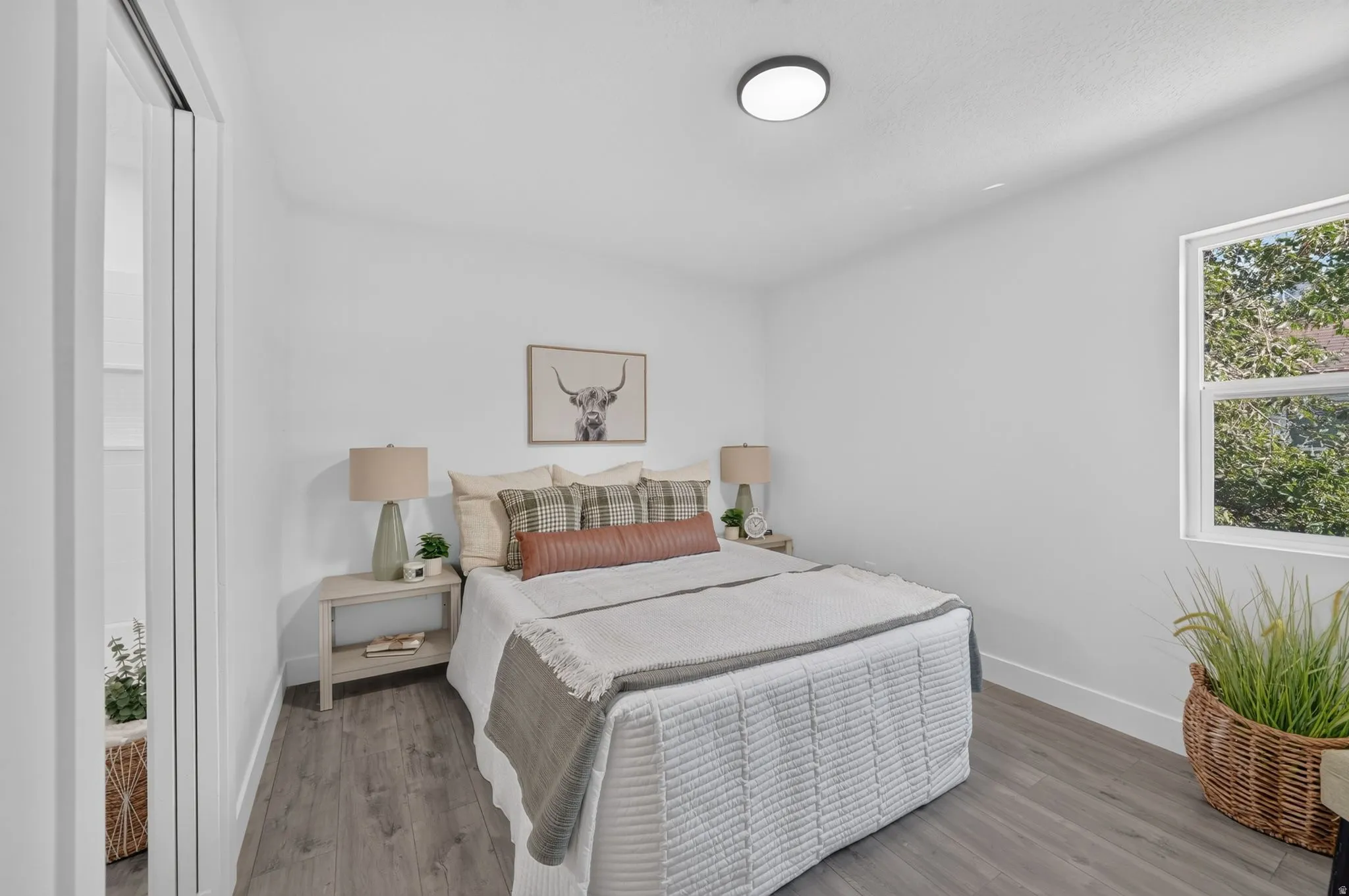 Bright room featuring wood-finish flooring, and a window with exterior tree views