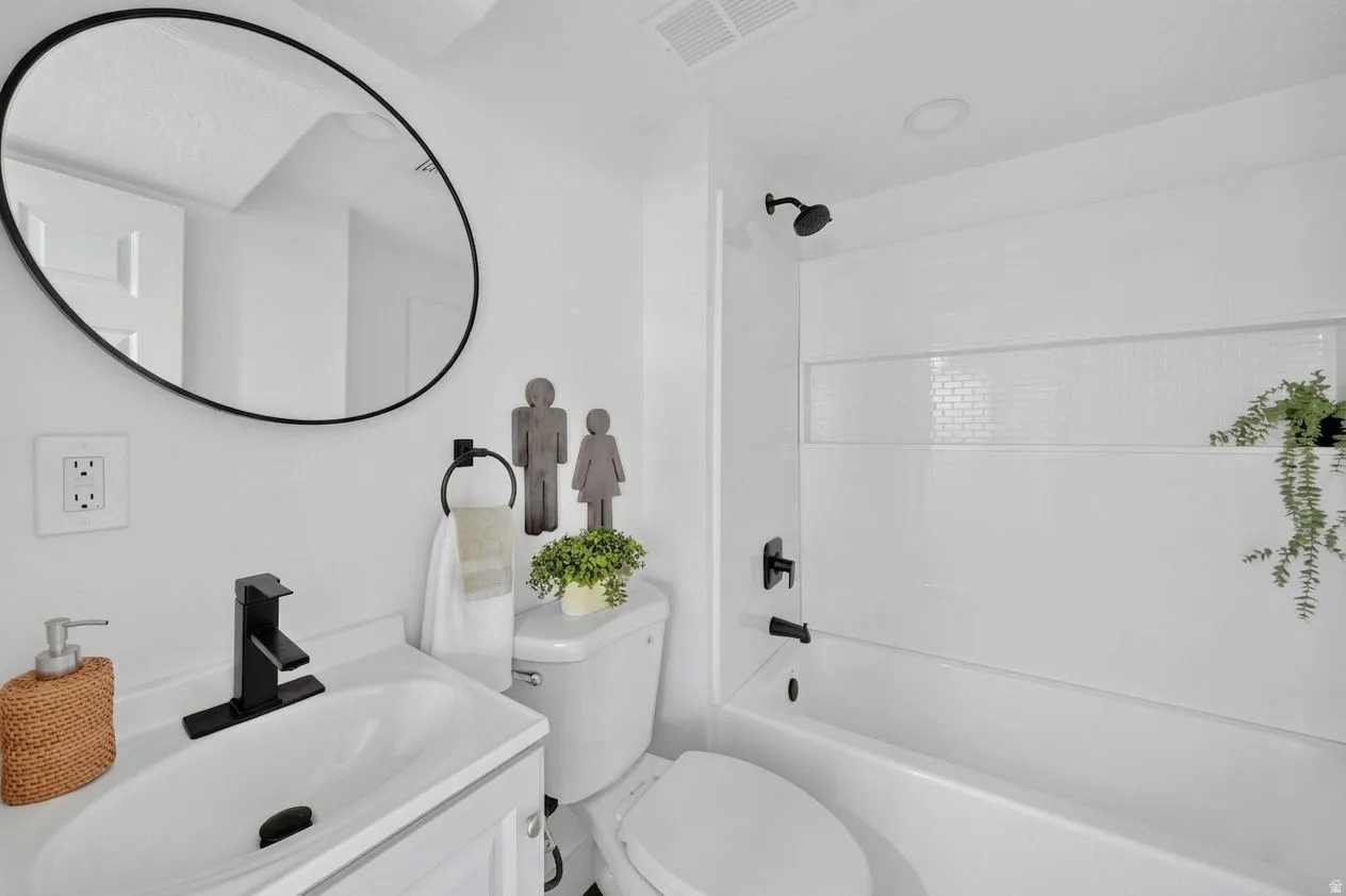 Bathroom featuring a single vanity with a white basin sink and matte black faucet