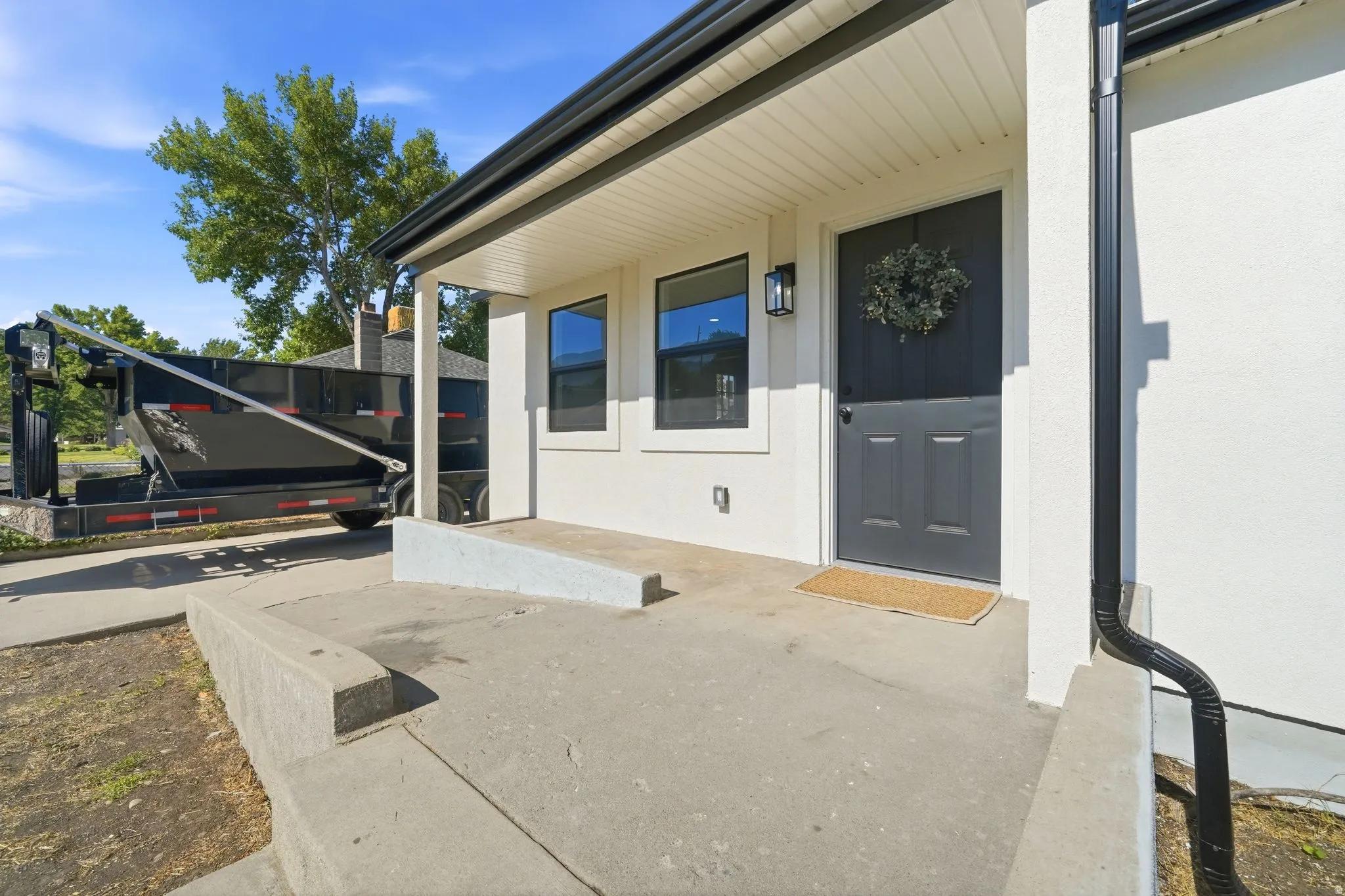 Exterior entry featuring a white facade, black trim, and a covered porch