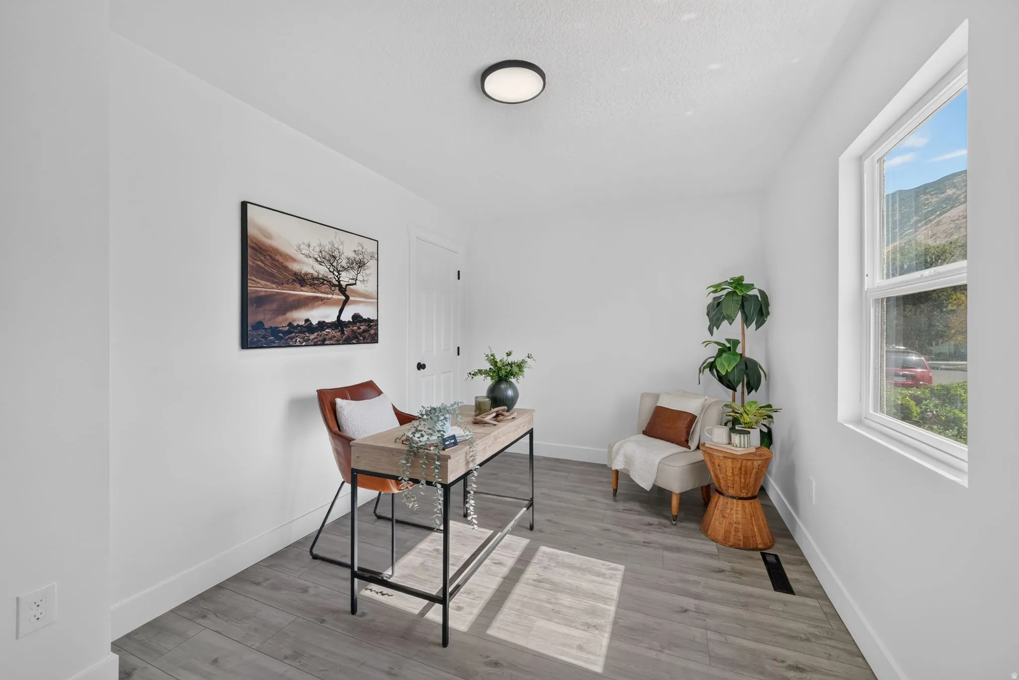 Bright interior space featuring light wood-finish flooring, white walls, and a single pane window
