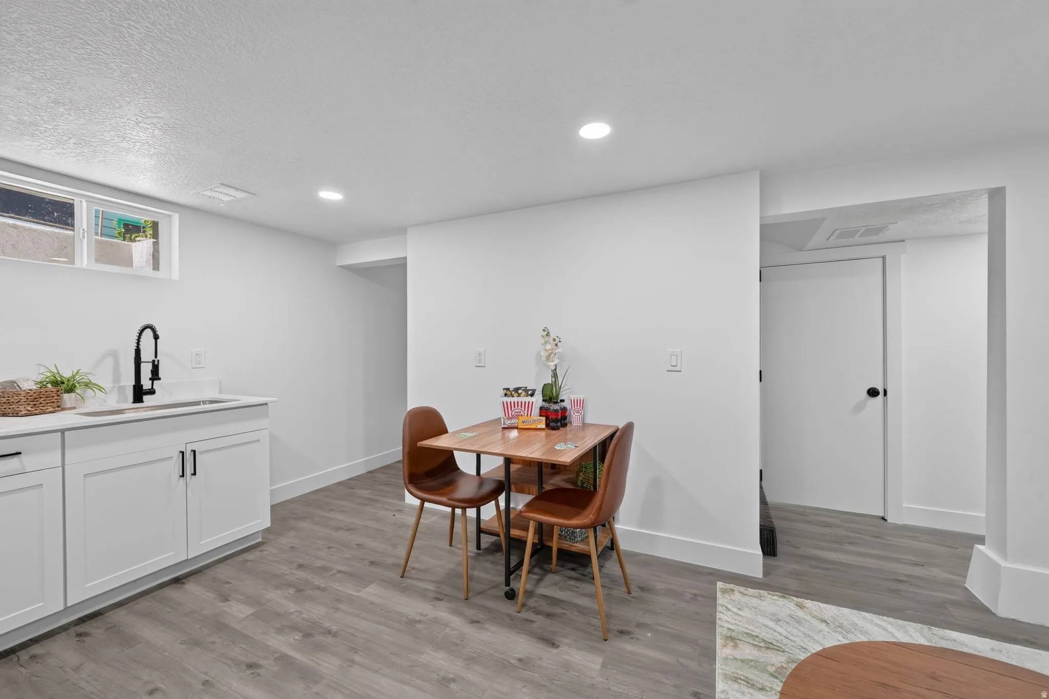 Kitchenette featuring white shaker-style cabinetry, a single basin sink with a matte black gooseneck faucet, and quartz-finish countertops