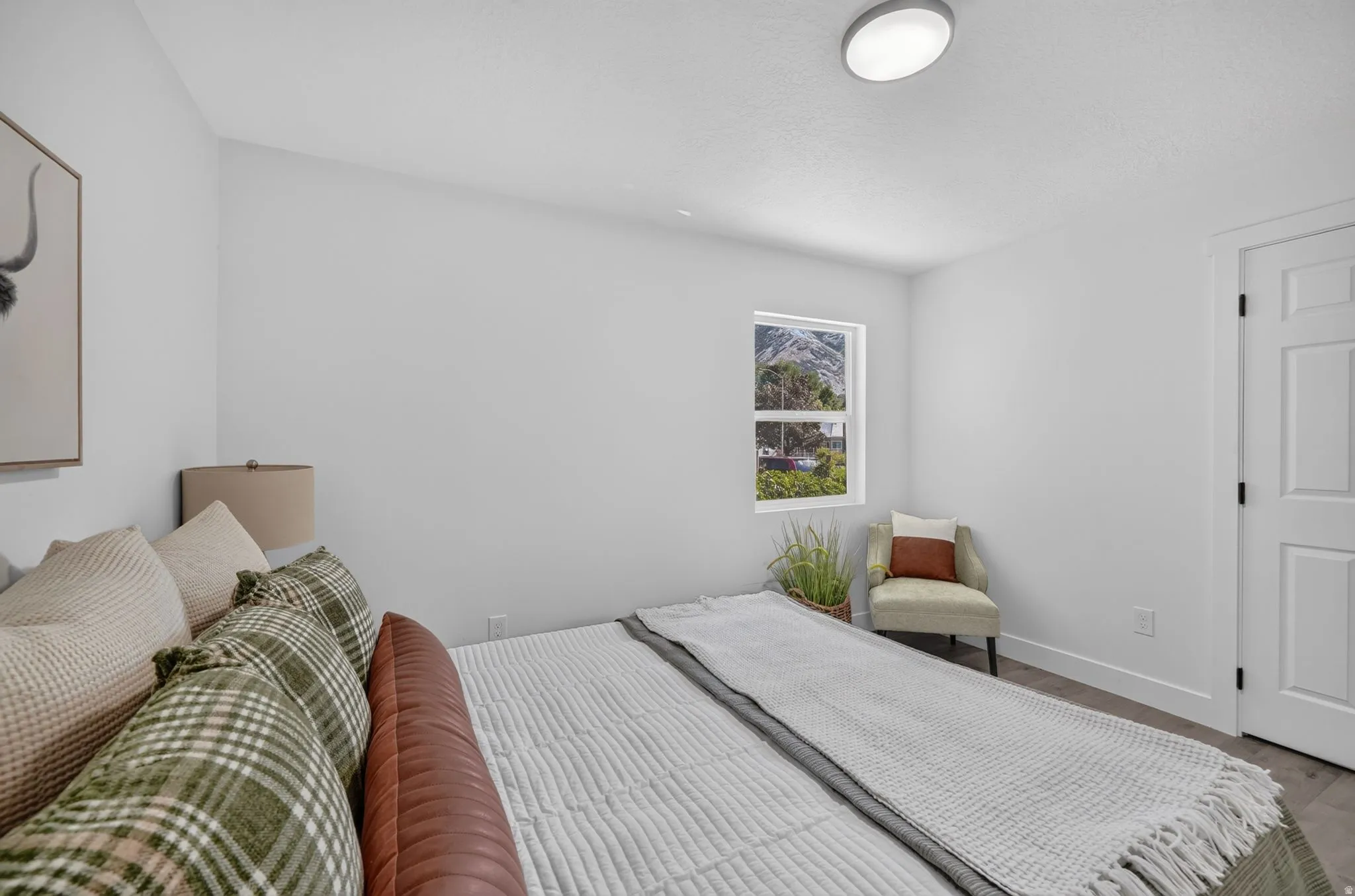 Bedroom featuring a window with mountain scenery, a solid core door, and wood-finish flooring