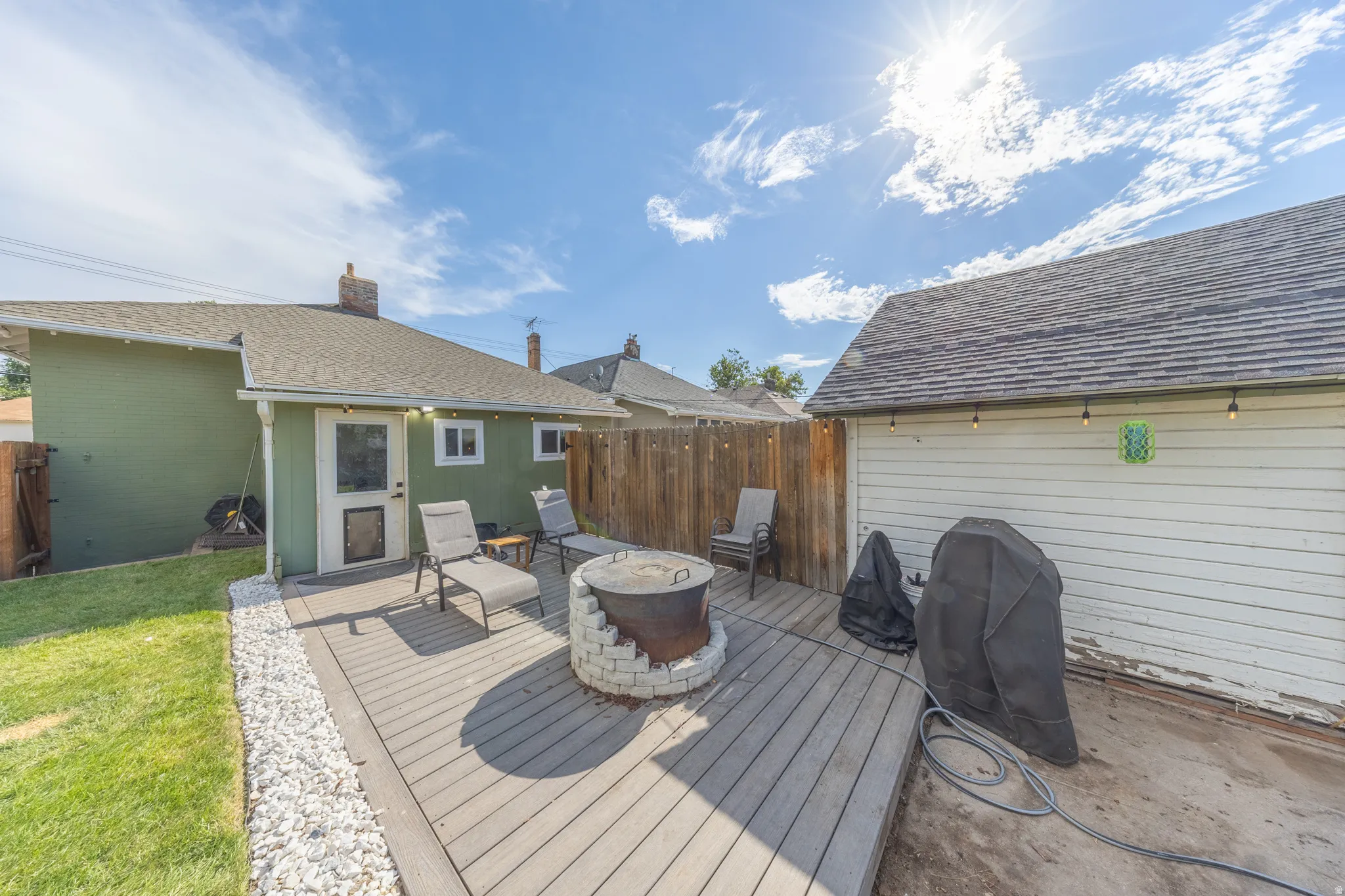Outdoor living area featuring composite decking, a built-in stone fire pit, and a fenced perimeter