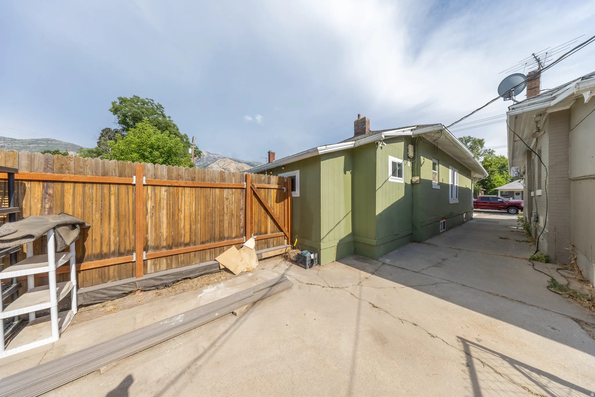 Rear exterior with concrete paving, wood plank fencing, and a painted siding finish
