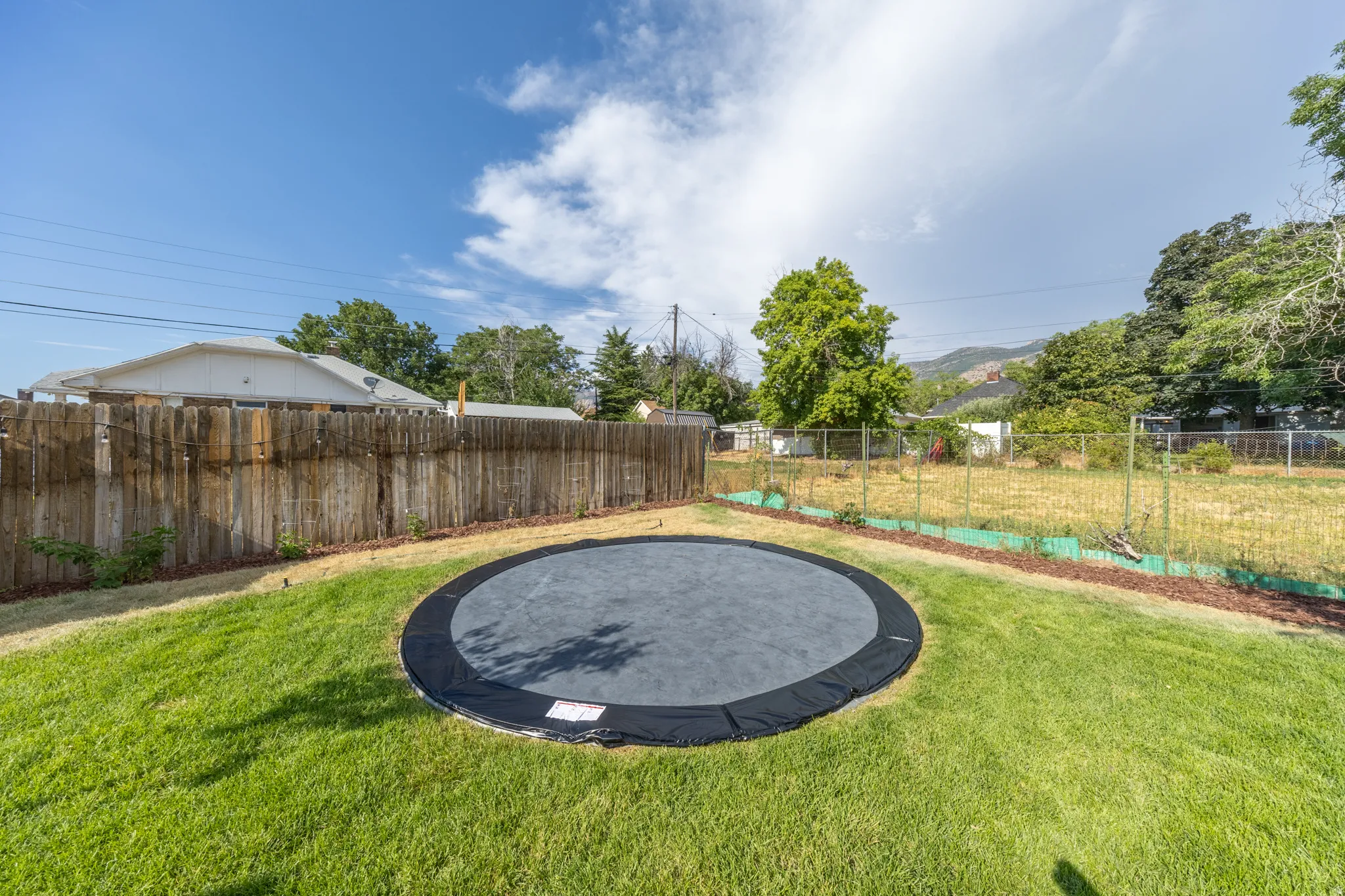 Expansive green lawn featuring an in-ground round trampoline