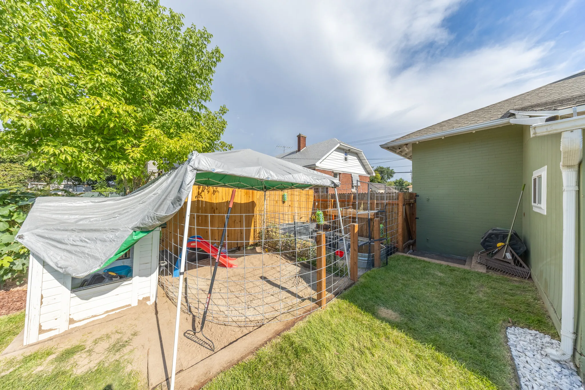Side yard featuring a grass lawn, white gravel strip, and a wood fence enclosing a separate area