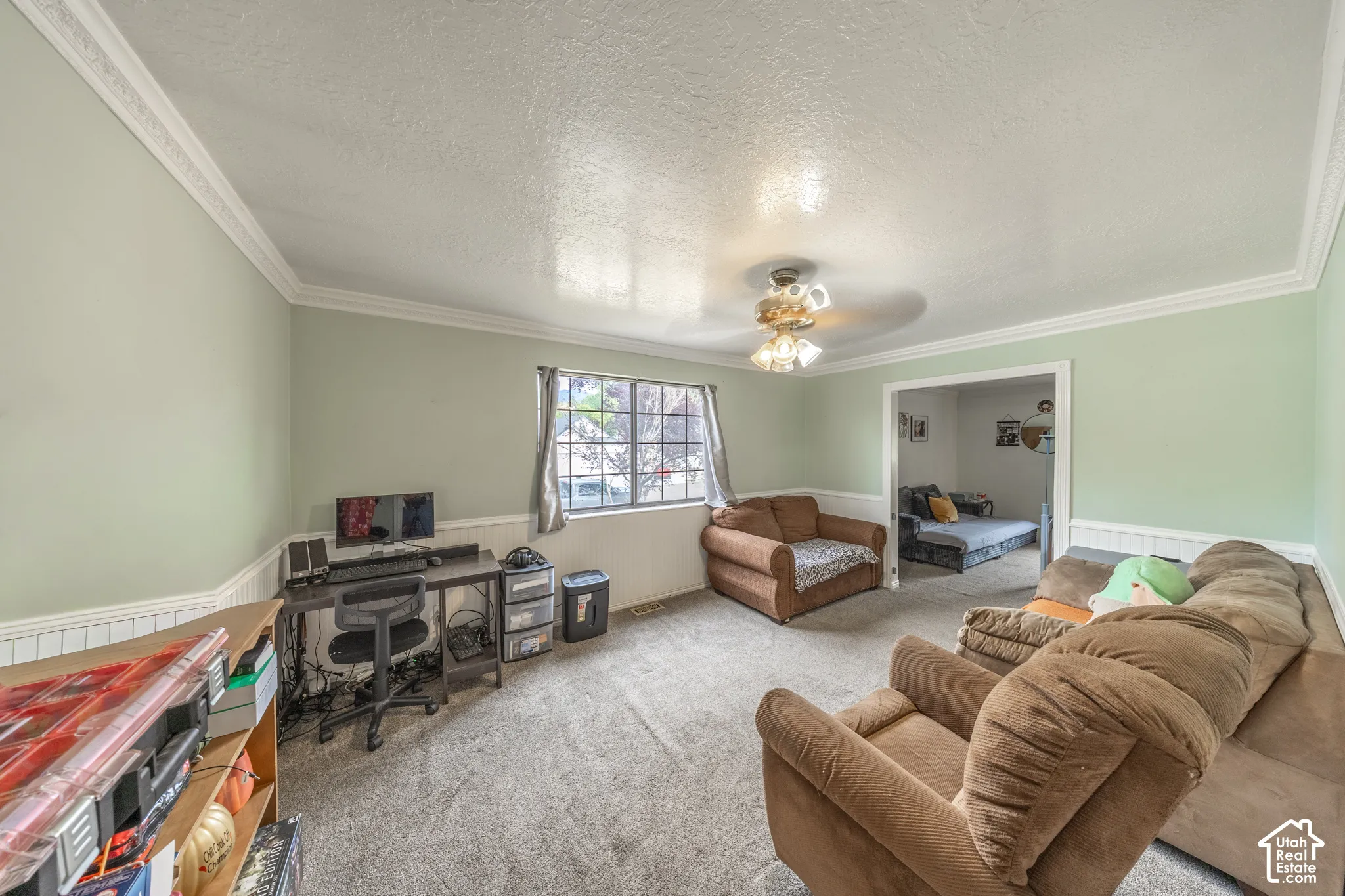 Spacious room featuring light green walls with white wainscoting and crown molding