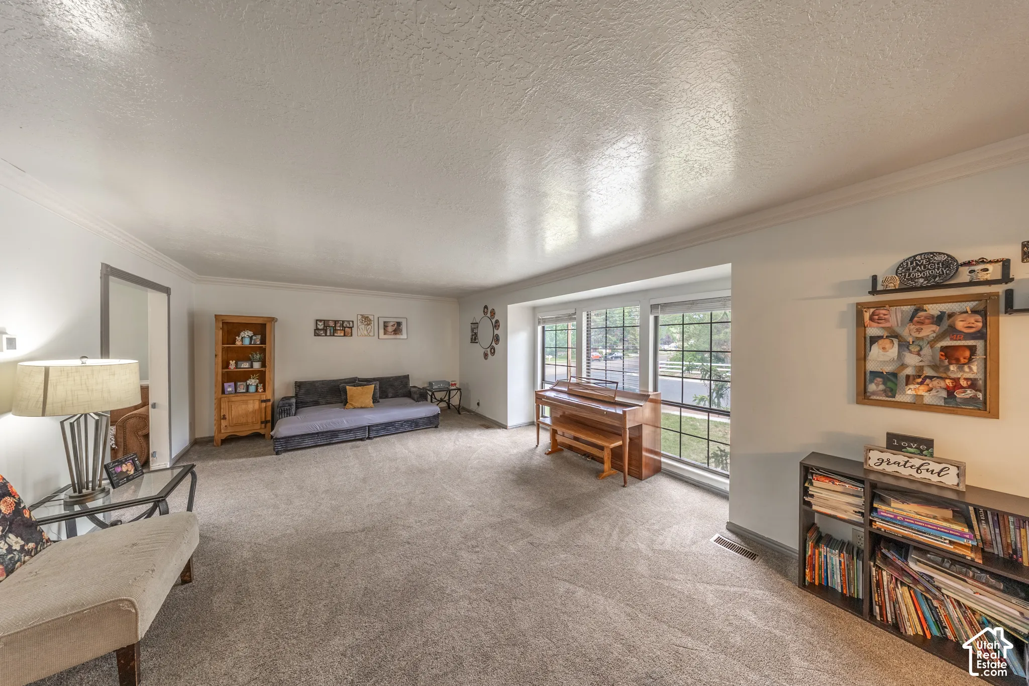 Carpeted living area featuring a large picture window, crown molding, and a built-in wall niche