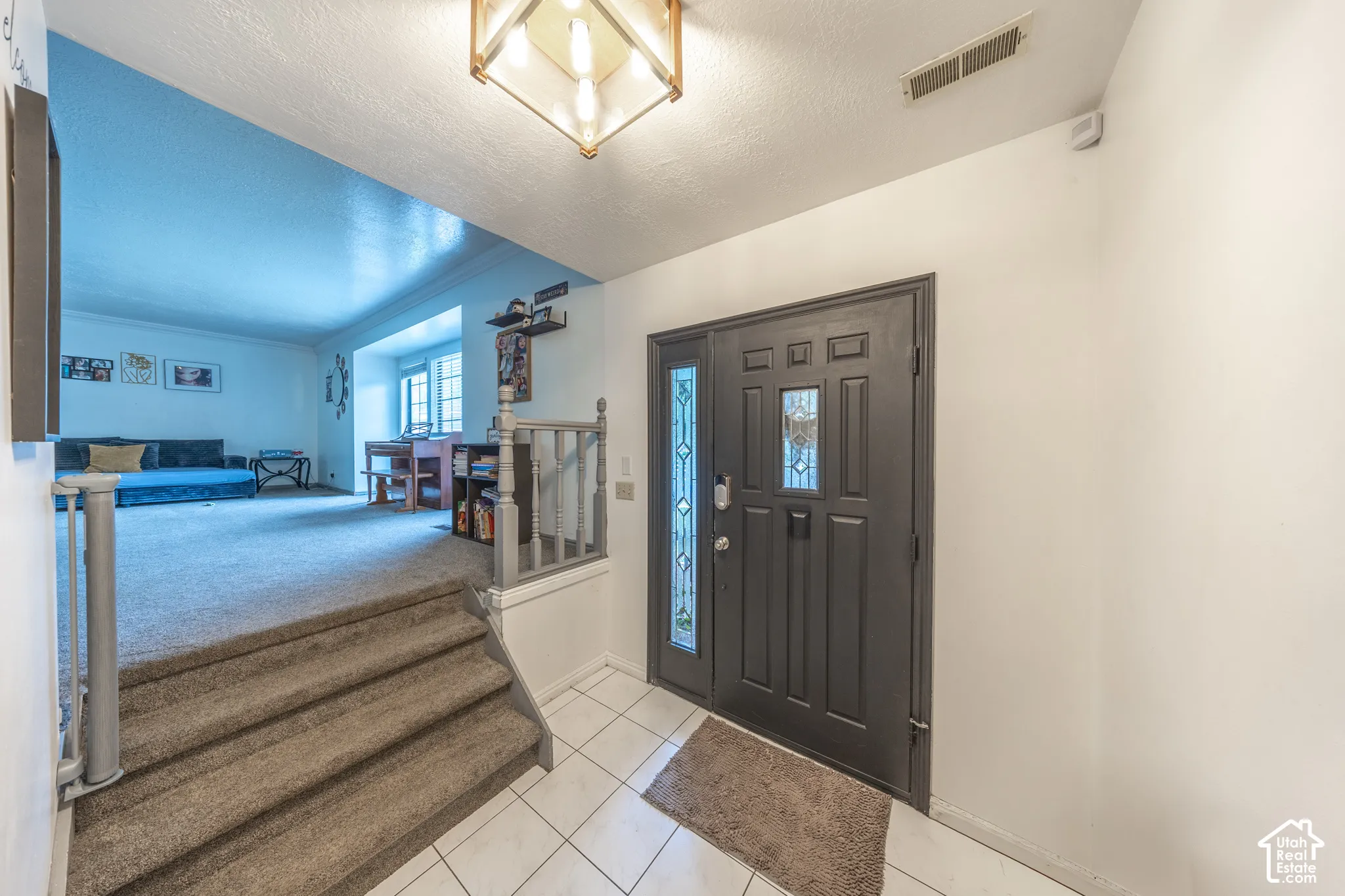 Entryway featuring a dark paneled door with decorative glass inserts, white tiled flooring, and an overhead light fixture