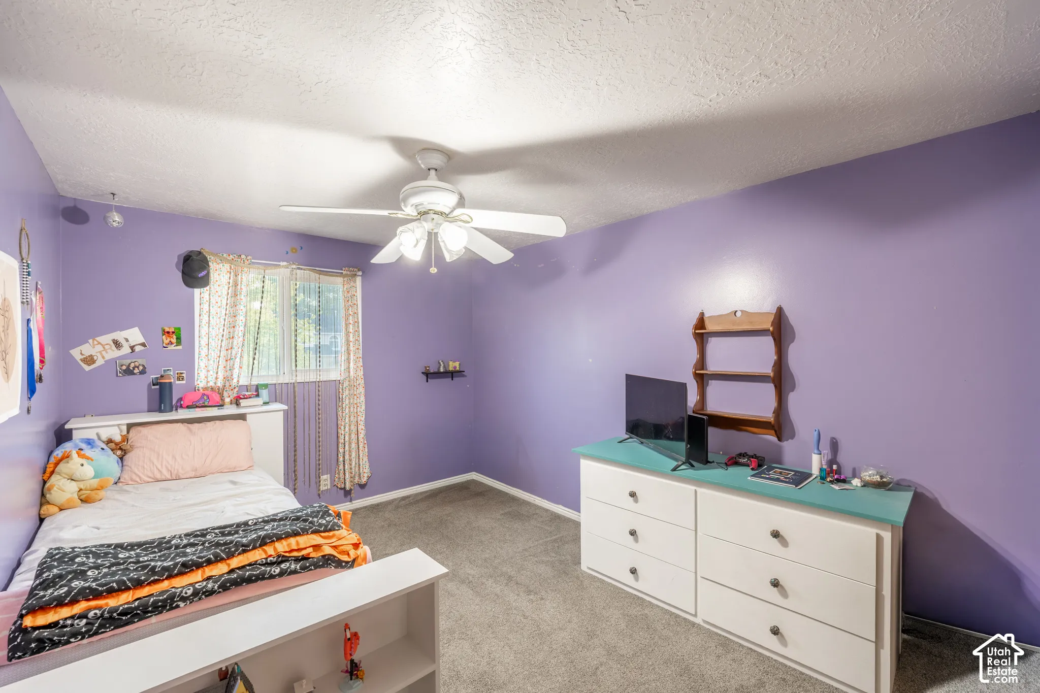 Ceiling fan, wall-mounted shelving, built-in headboard, window with natural light, and carpeting