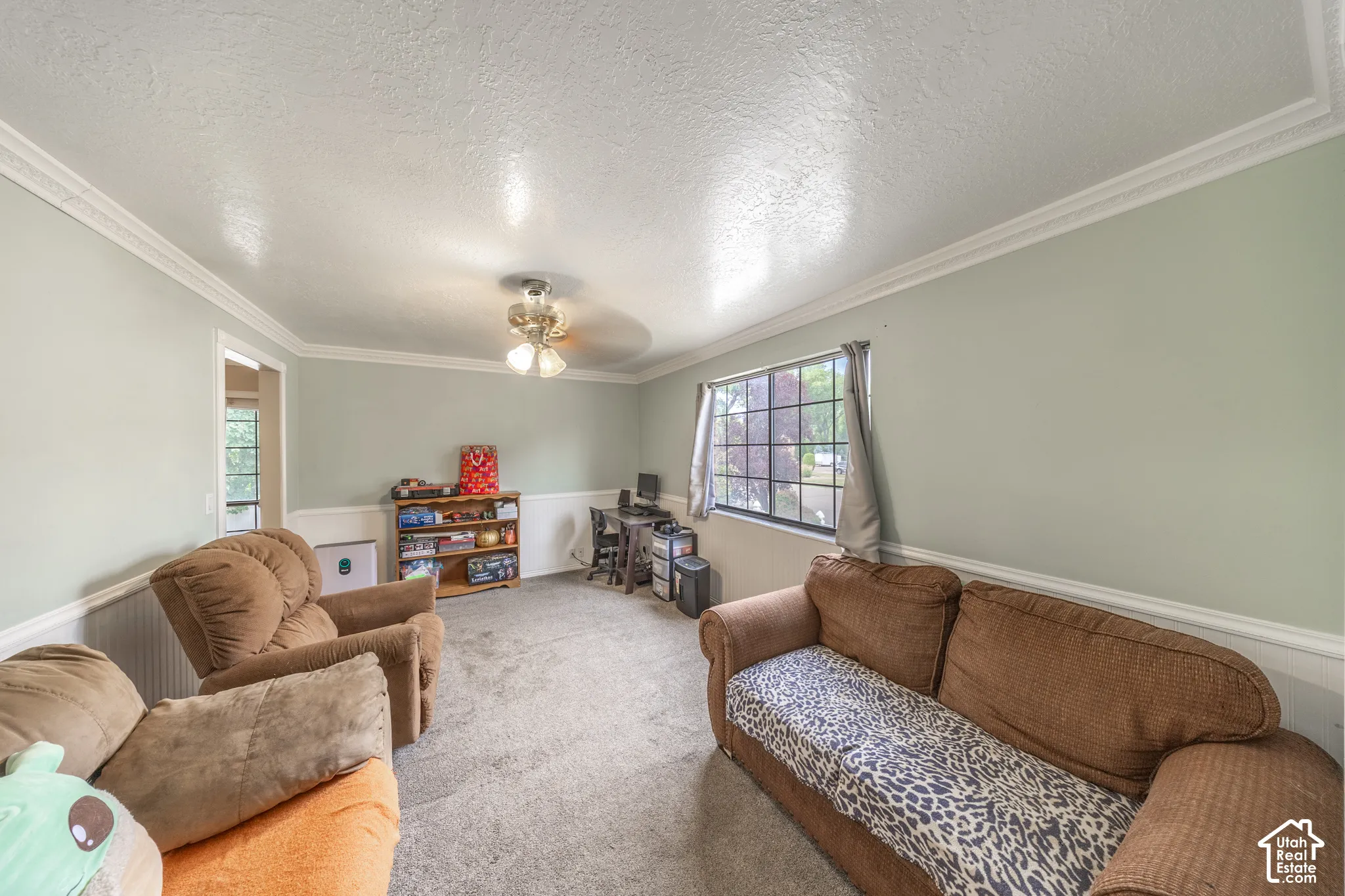 Spacious room featuring light green walls, white crown molding, and wainscoting