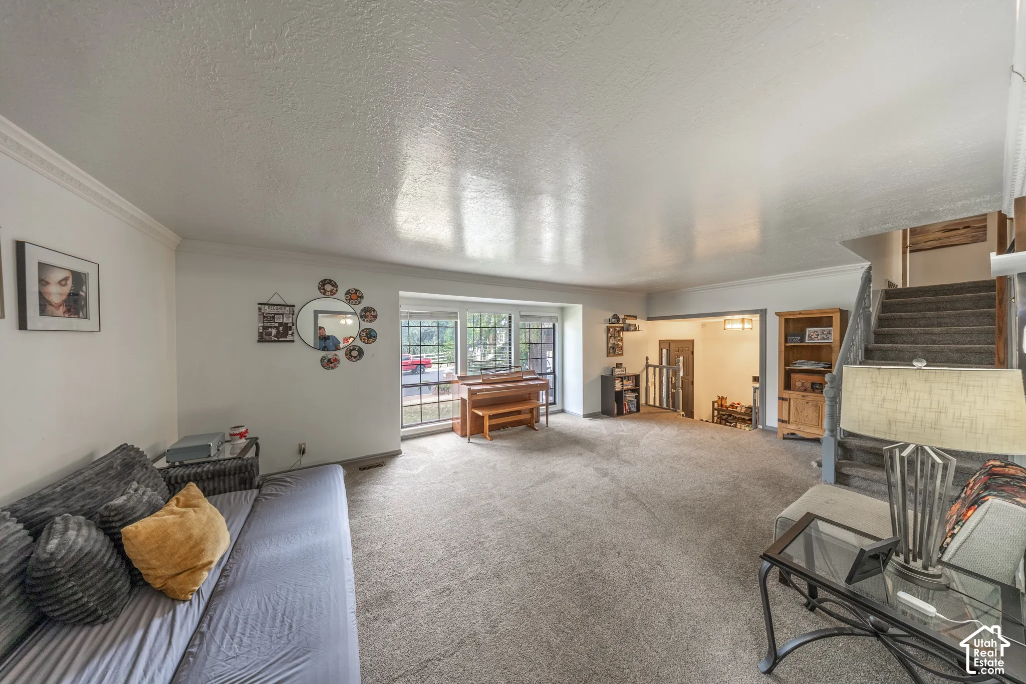 Open concept living area with broadloom carpeting and white crown molding